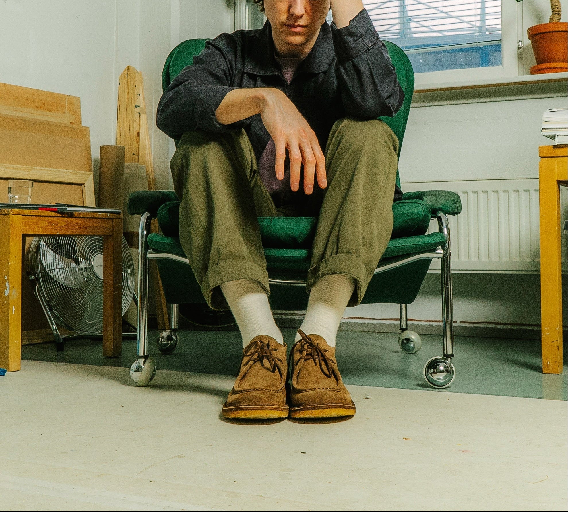 Person sitting in a chair in a room with tables, chairs, and plants.